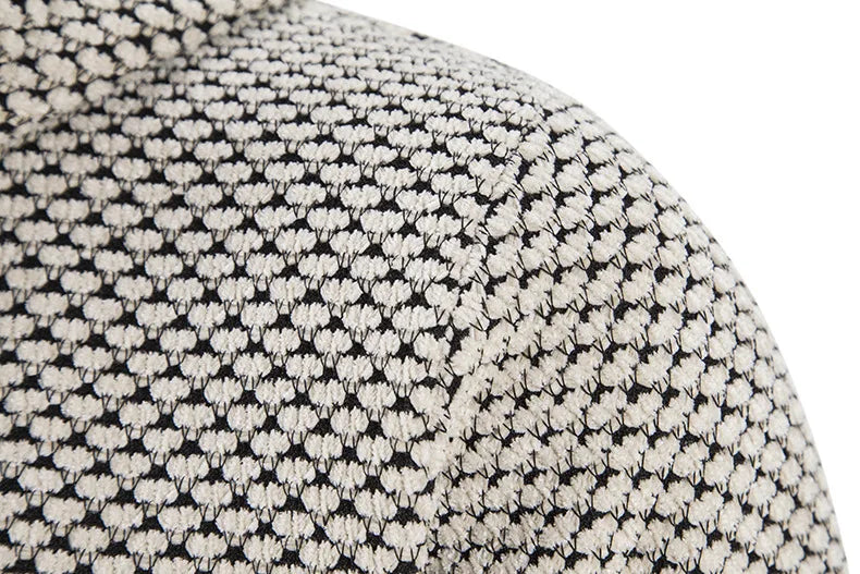 Men’s knit sweater fabric detail, beige and dark speckled texture with stitched pattern.