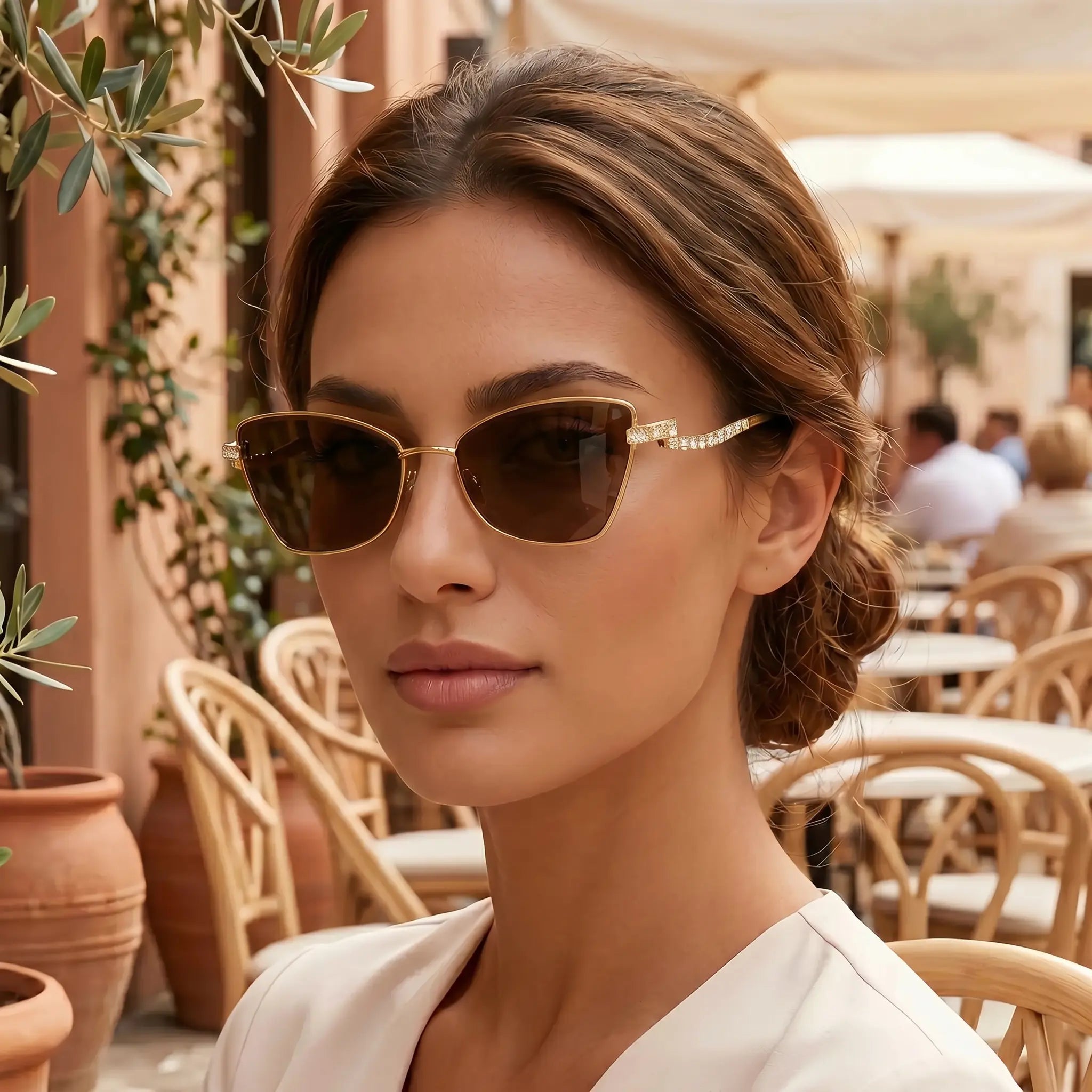 Cat-eye sunglasses with gold-tone metal frame, dark lenses, and rhinestone accents at temple