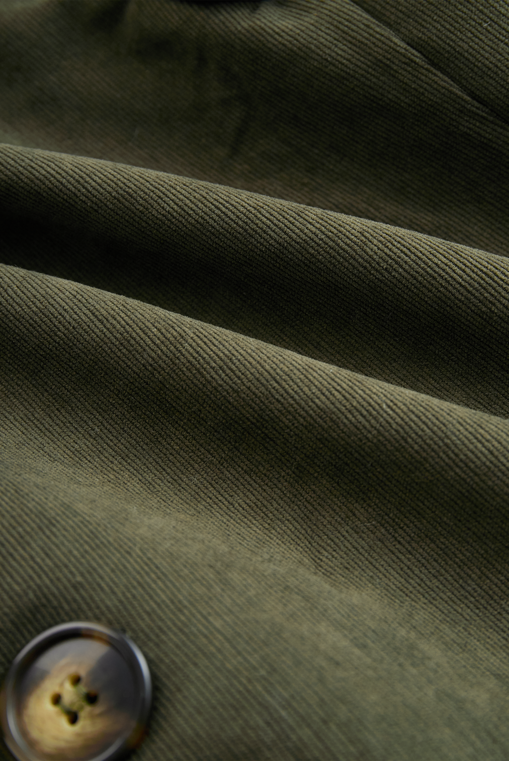 Military green corduroy jacket fabric close-up with fine ribbed texture
