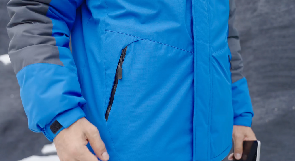 Blue winter jacket close-up with zip pocket detail and hood seam.