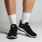 Men's black hiking shoes with ribbed white socks, padded collar, and orange-accent tread