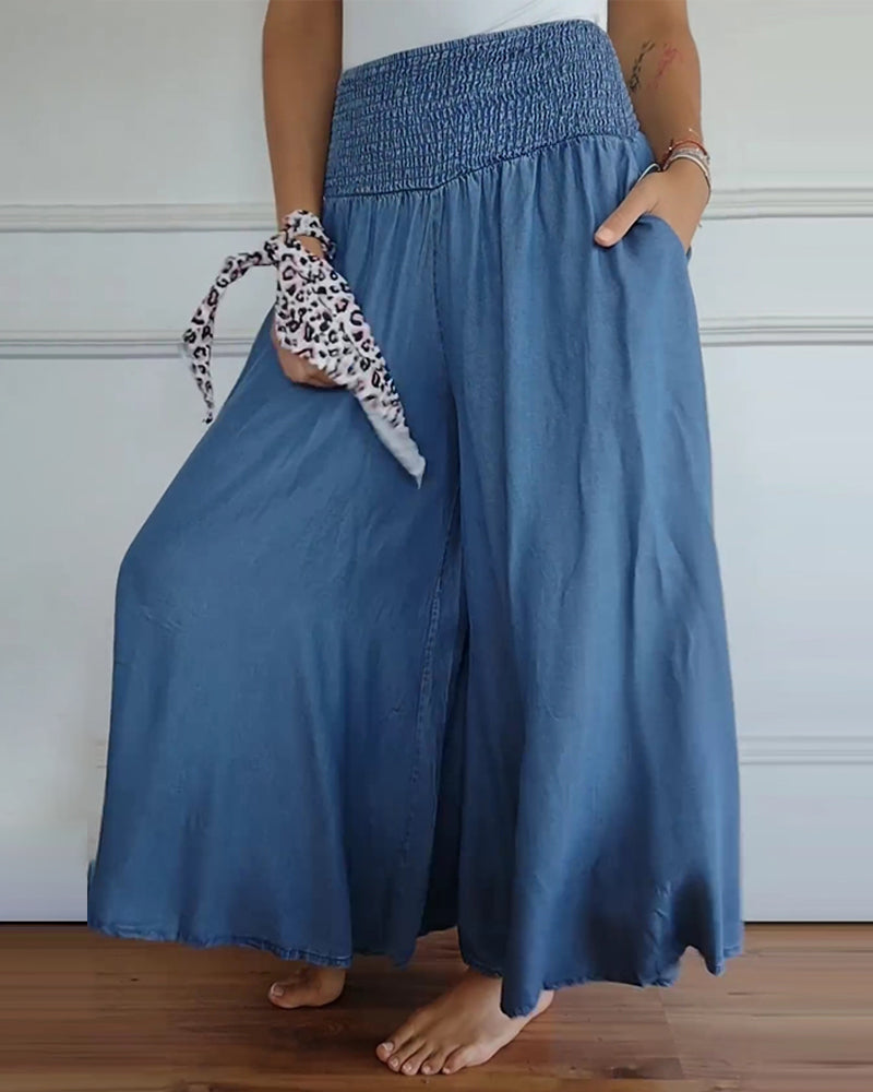 High-waisted wide-leg trousers with smocked elastic waistband, denim blue, side view.