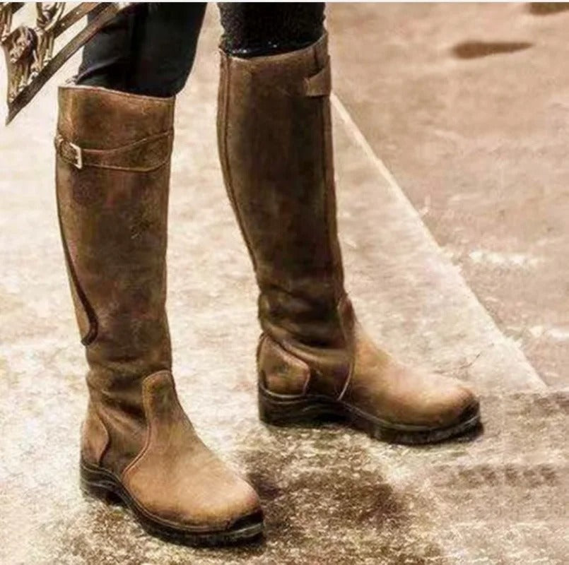 Knee-high waterproof brown boots with buckle strap and low-profile rugged sole