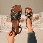 Black criss-cross flat sandals with square toe, cushioned comfort straps.