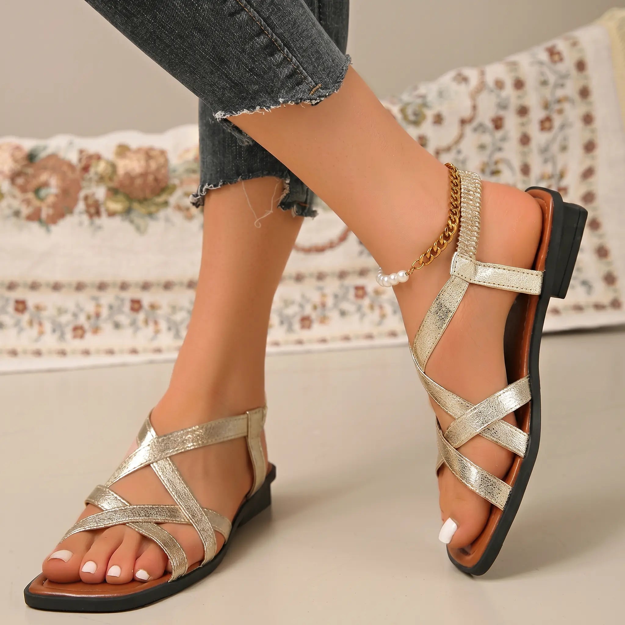 Champagne shimmer square-toe flat sandals with criss-cross straps and cushioned sole.