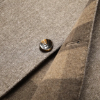 Close-up of brown heather jacket fabric with metal-button detail on lapel