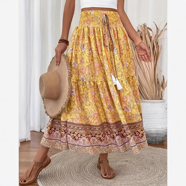 Long tiered skirt with yellow floral print, elastic waistband, patterned hem border.