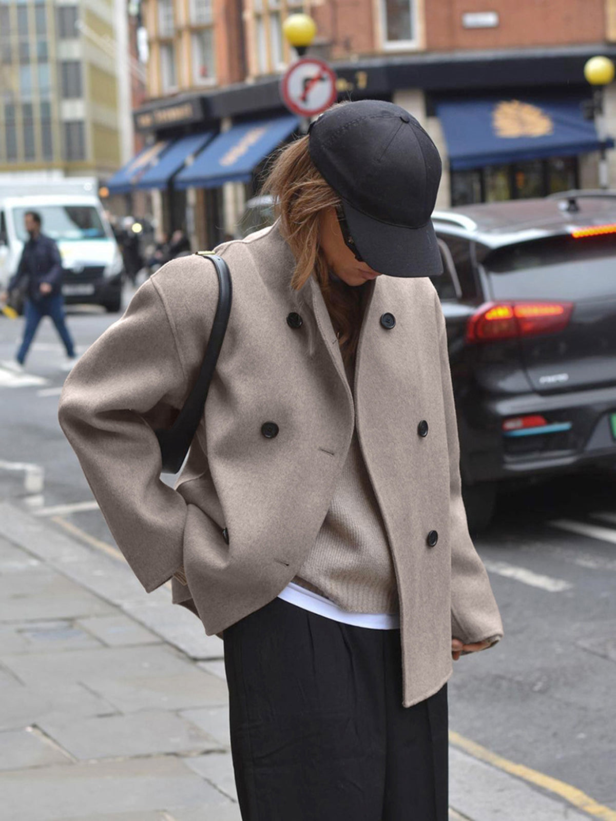 Taupe double-breasted pea coat on model, dark button placket and structured shoulders