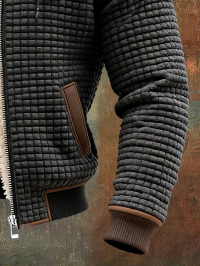 Black quilted insulated fleece jacket sleeve and pocket detail with brown leather trim