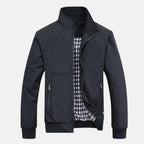 Men's dark windbreaker jacket with full zip, stand collar, and two front zip pockets.