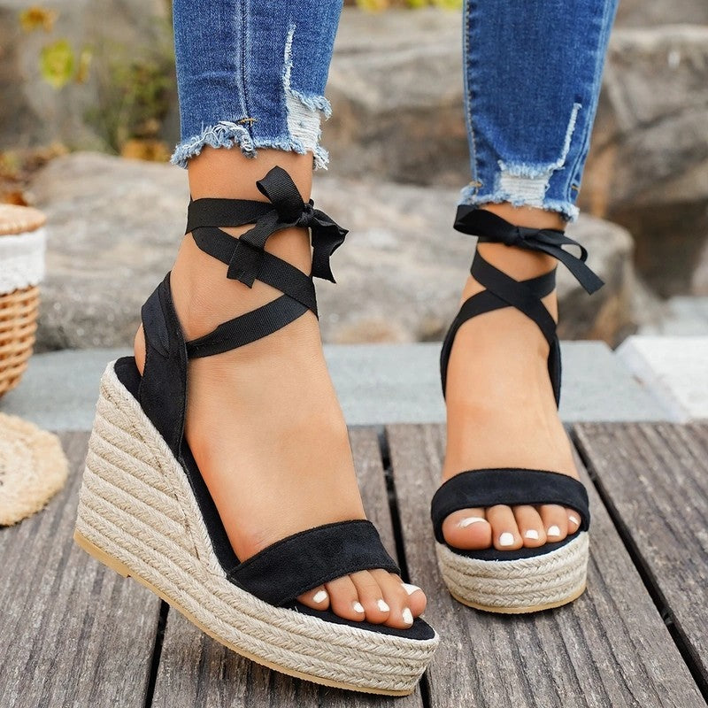 Black platform wedge sandals with crisscross ankle ties and open toe, back/side view