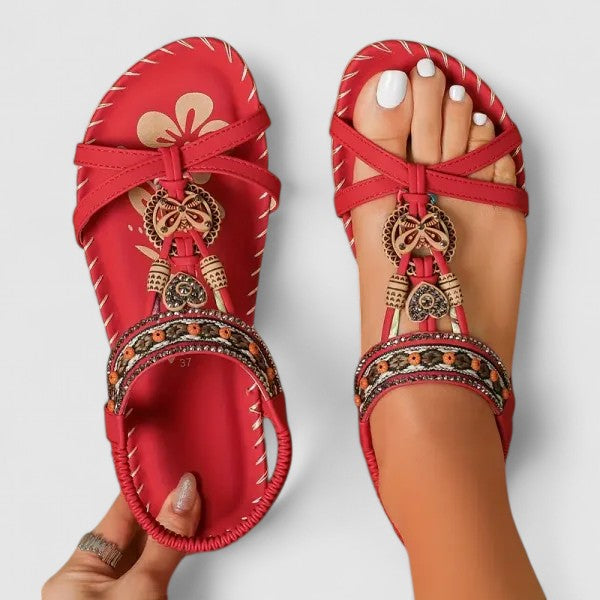 Red orthopedic cushioned strap sandals with ankle straps and ornate dangling charms
