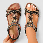 Beige orthopedic cushioned strap sandals with braided crisscross straps and ornate charms