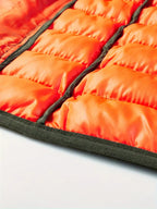 Quilted orange inner lining of a sleeveless bodywarmer vest, with black trim edge.