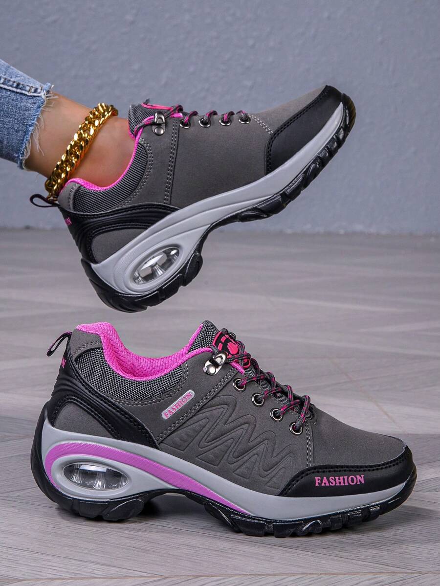 Pair of men’s hiking shoes, dark gray/black with bright pink lining and purple sole edge.