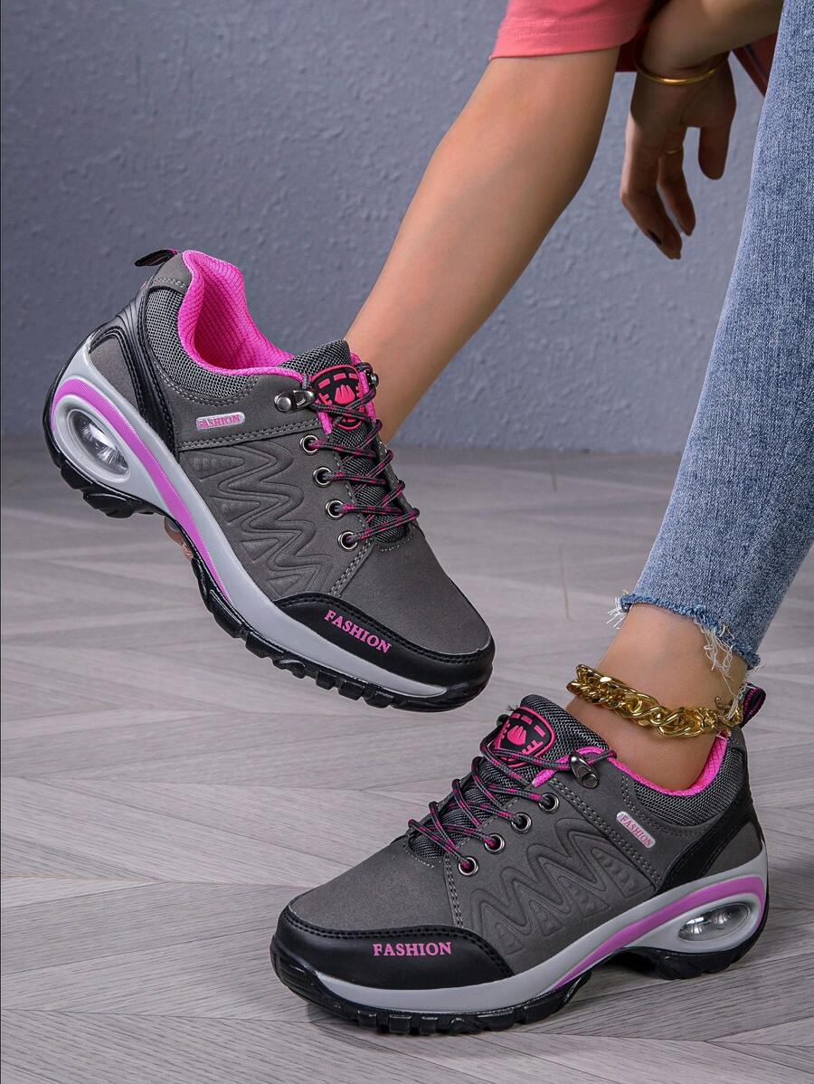 Men’s hiking shoe with dark gray/black upper, pink collar, lace-up, thick tread sole.