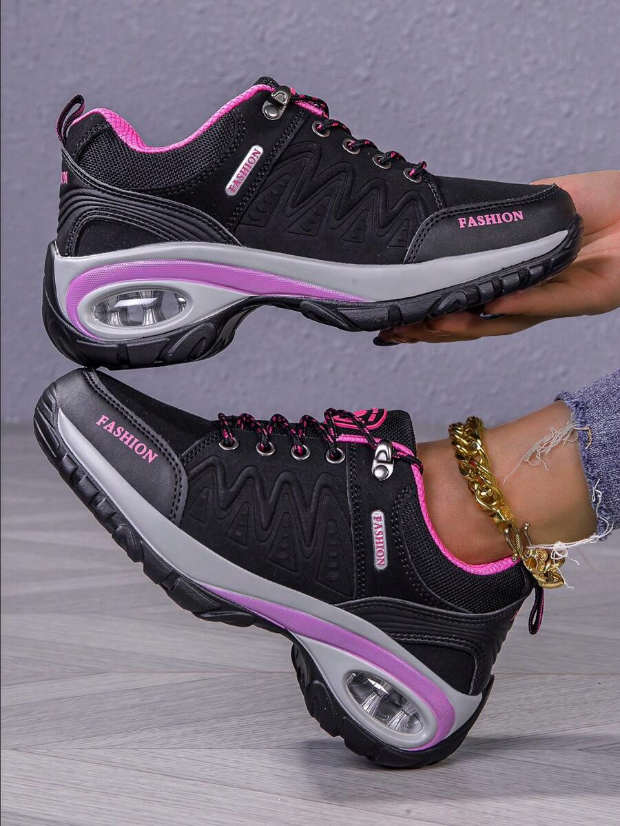 Men’s hiking shoe close-up: dark gray/black upper with pink trim and visible air unit sole.