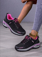 Men’s hiking shoes on feet: dark gray/black with pink accents, lace-up, chunky tread.