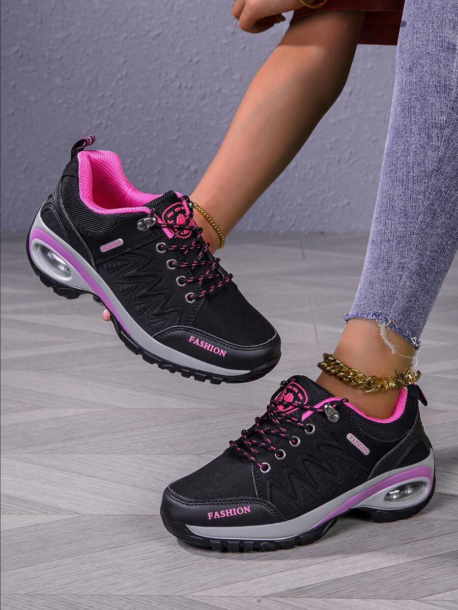 Men’s hiking shoes on feet: dark gray/black with pink accents, lace-up, chunky tread.