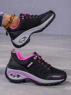 Men’s hiking shoe side view: dark gray/black upper, pink collar, purple edge, air sole.