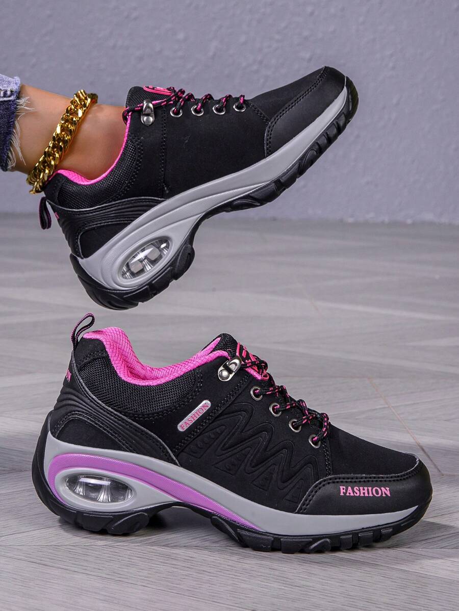 Men’s hiking shoe side view: dark gray/black upper, pink collar, purple edge, air sole.