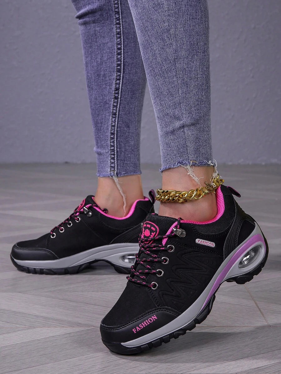 Men’s hiking shoe front view: black upper with pink laces, purple trim, sturdy tread sole.