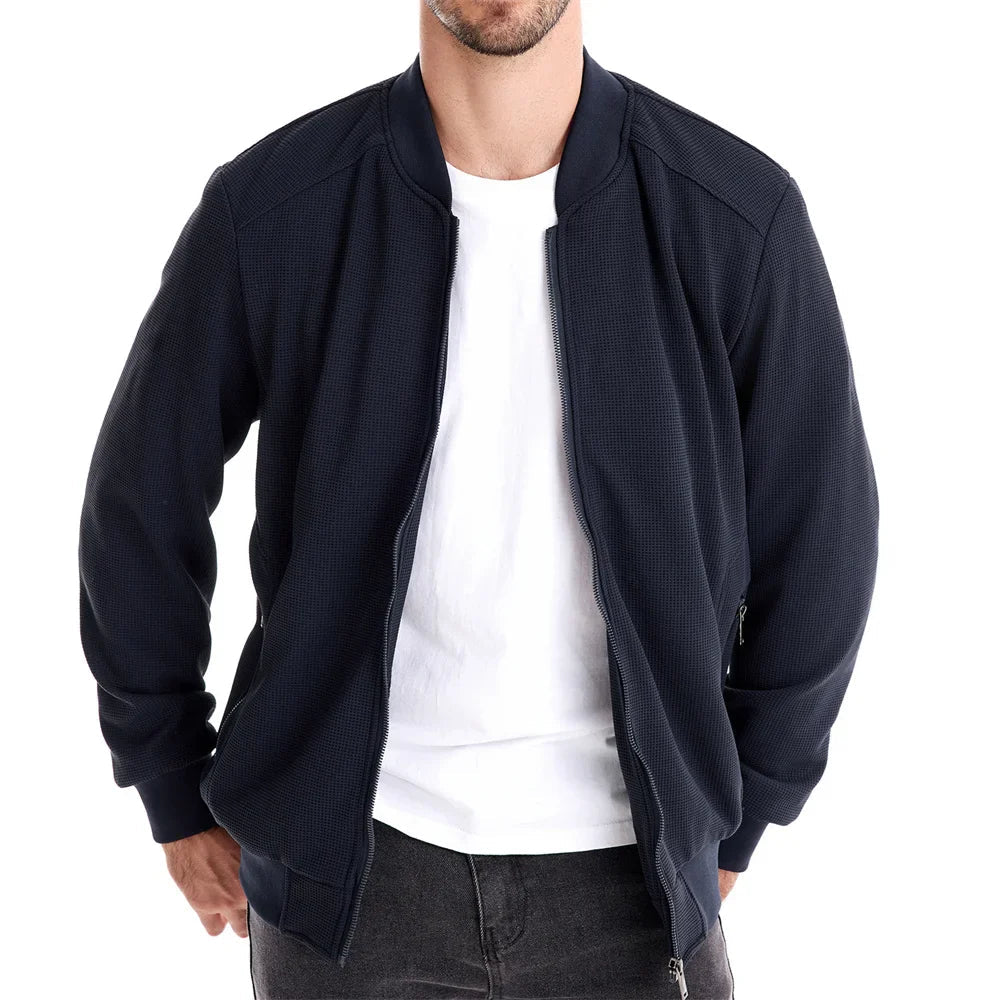 Men's navy zip-up bomber jacket worn open with stand collar and ribbed cuffs