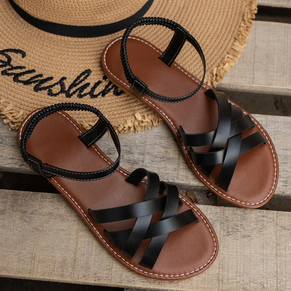 Black flat open-toe sandals with crisscross straps and stitched ankle strap