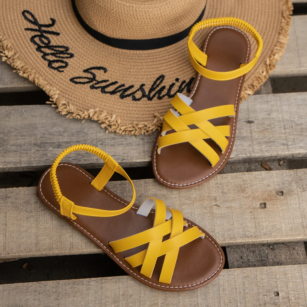 Yellow flat open-toe sandals with woven-style crisscross straps and stitched sole