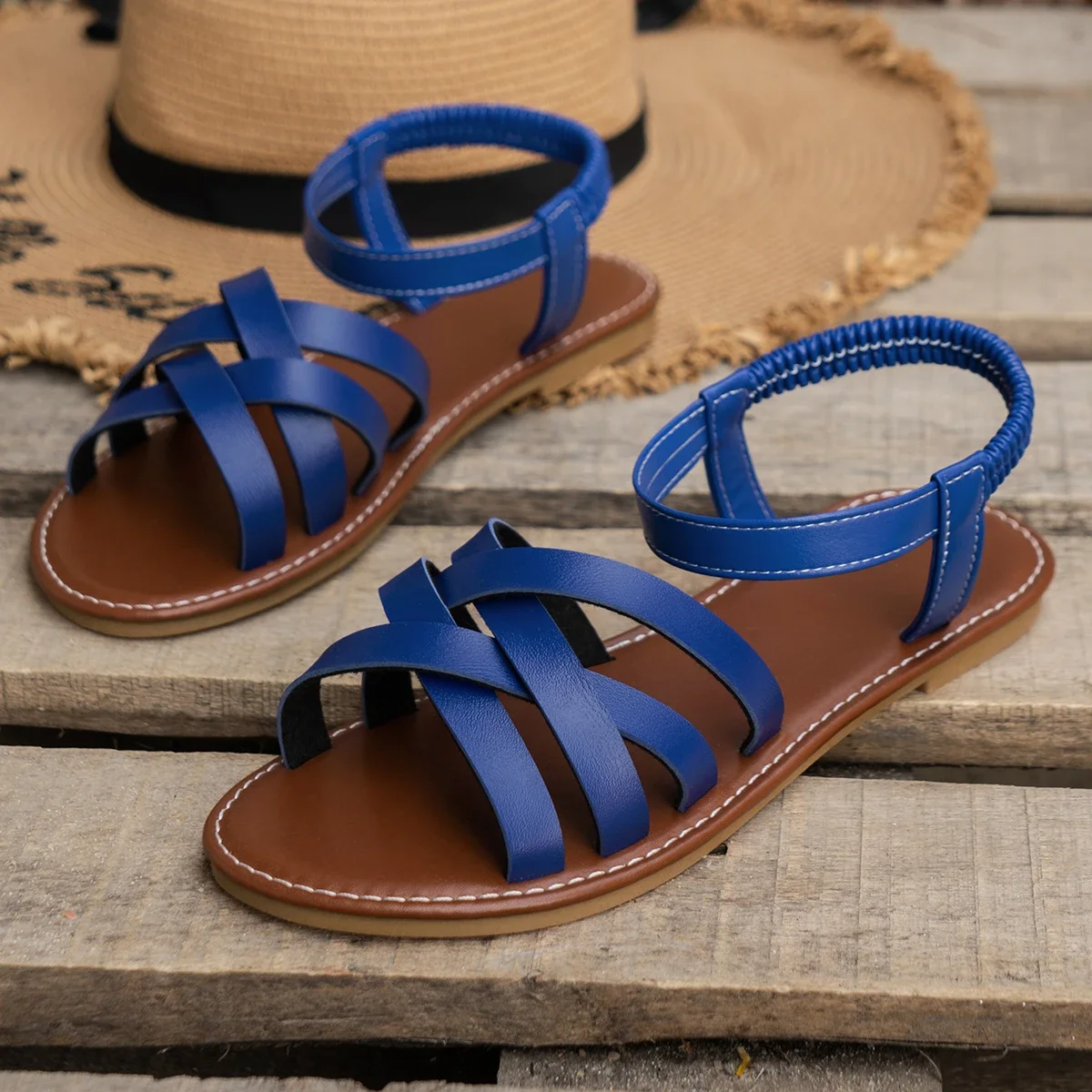 Blue flat open-toe sandals with wide crisscross straps and stitched ankle strap