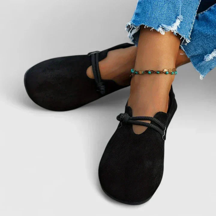 Black slip-on loafer pair with round toe and elastic strap, worn with jeans