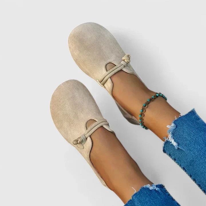 Beige slip-on loafers with round toe and gathered elastic strap, worn with blue denim