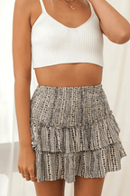Women's mini skirt with tan-and-black abstract print tiered ruffles and elastic waist.