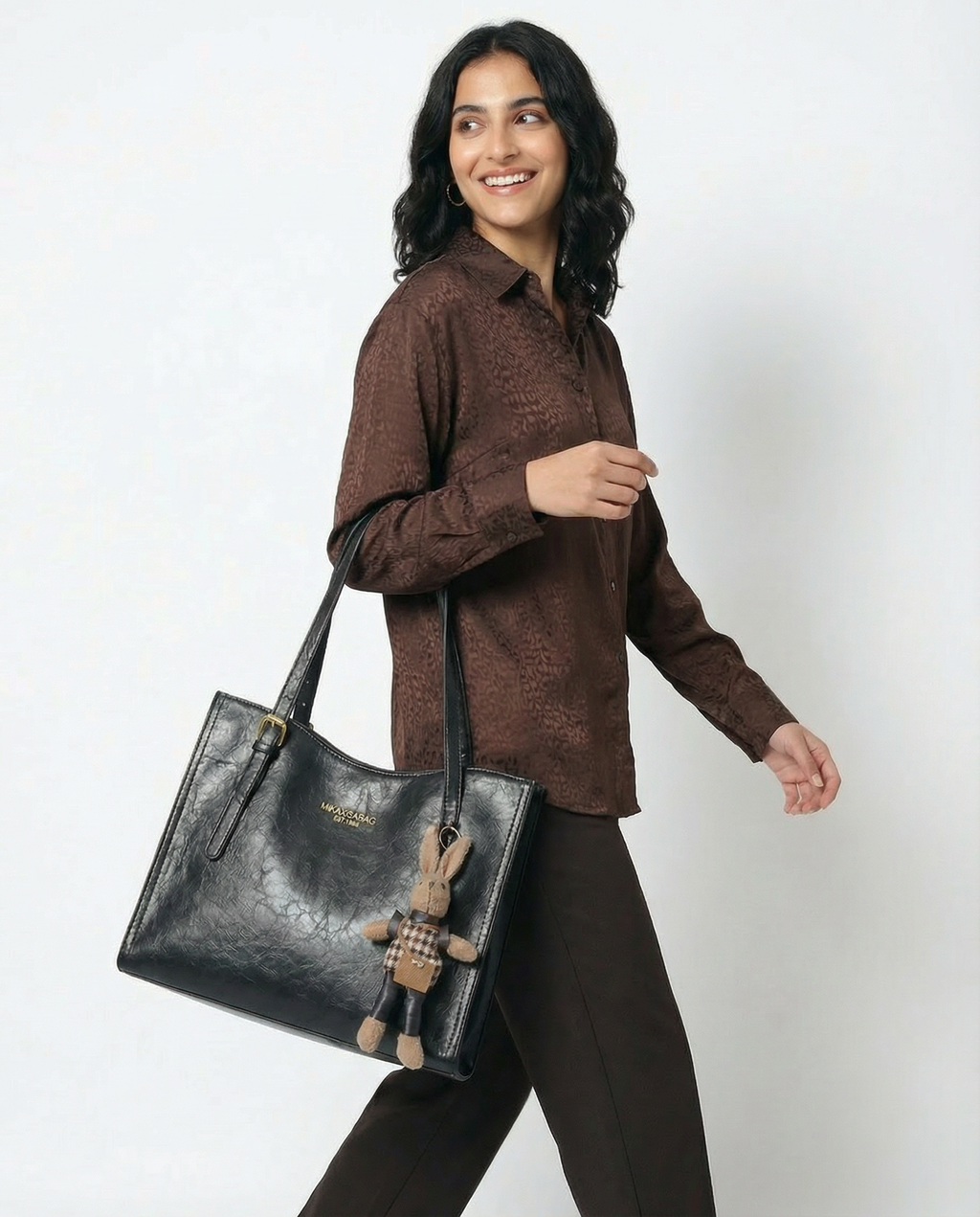 Dark vegan leather crossbody tote bag with top handles and bunny charm keychain accessory.