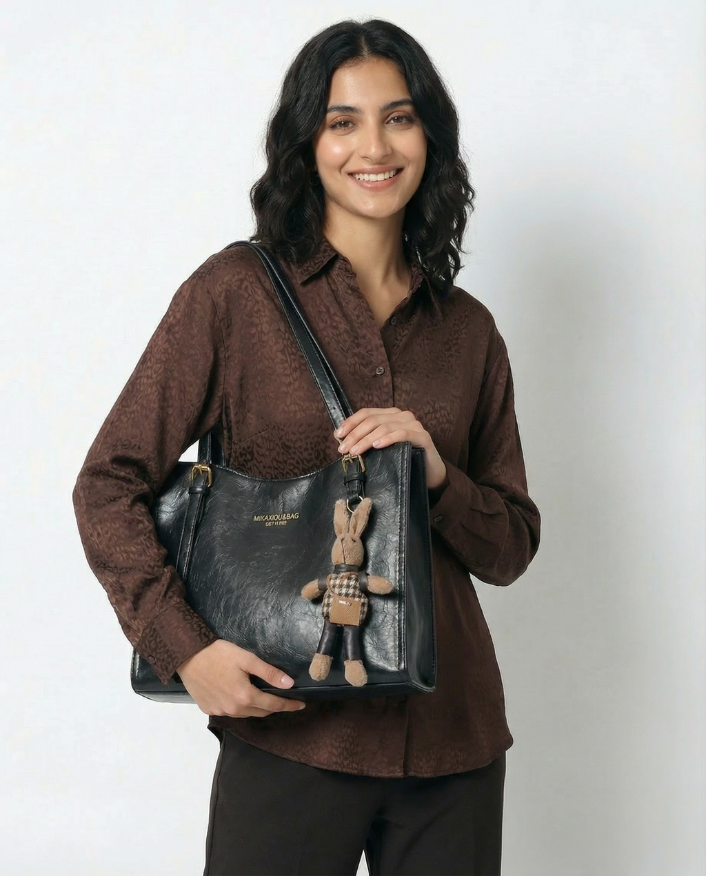 Black vegan leather small tote crossbody bag with front logo and bunny charm keychain.