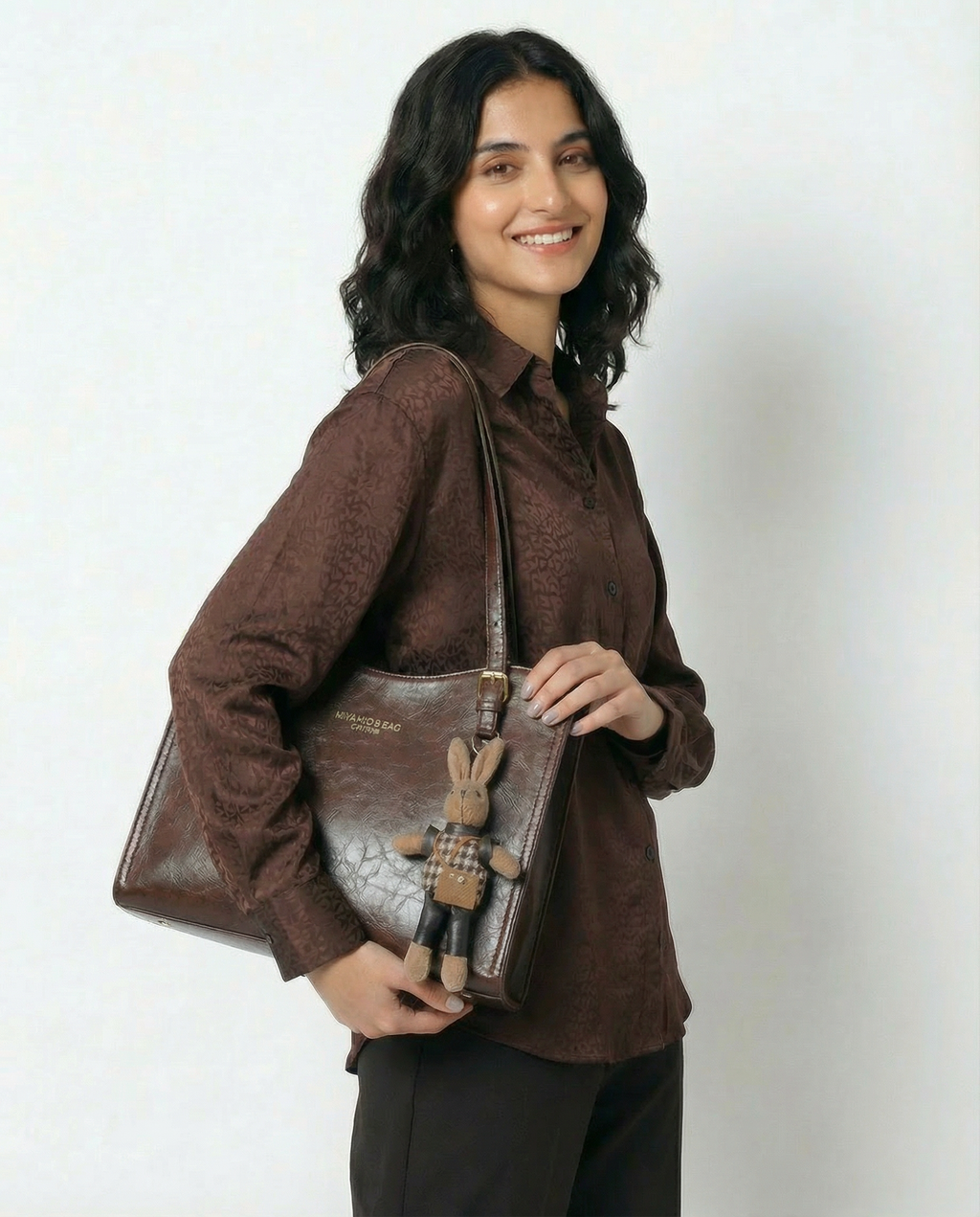 Brown vegan leather small crossbody tote bag with top handles and hanging bunny charm.