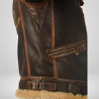Brown leather flight jacket detail with grommeted strap panel and fur-trim hem