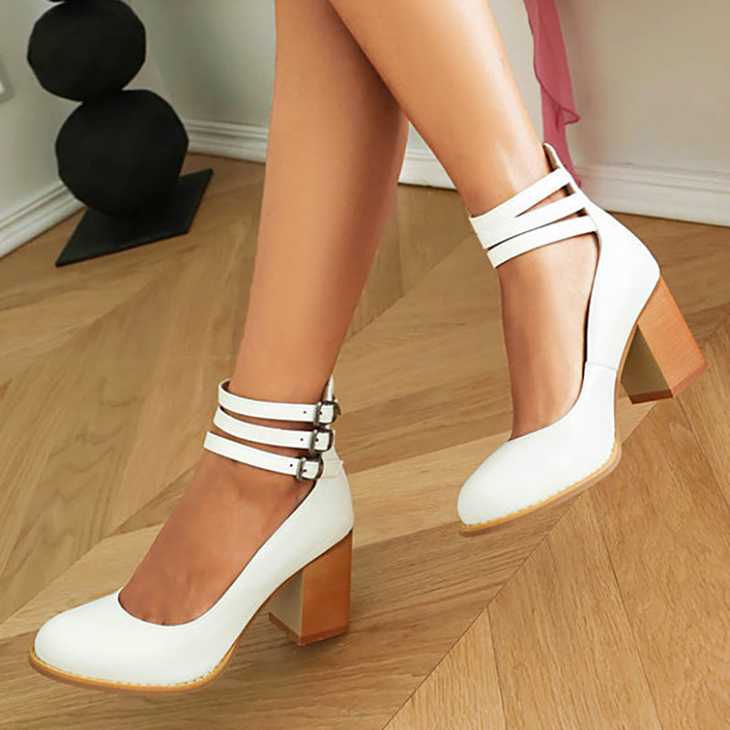 White triple-buckle block heel ankle strap pumps with three strap bands and buckles.
