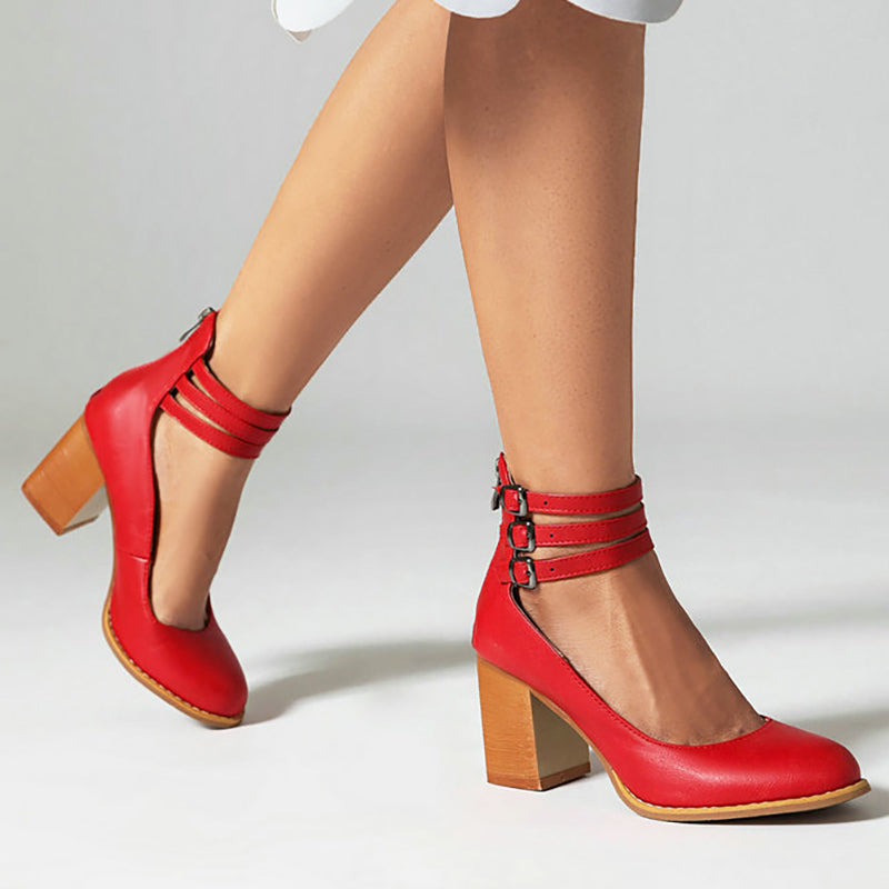 Red triple-buckle block heel ankle strap pumps with stacked straps and square toe.