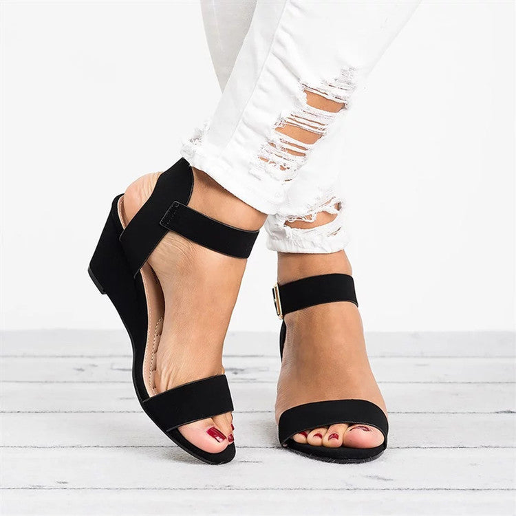 Women's black wedge sandals, open toe with adjustable ankle strap, side view.