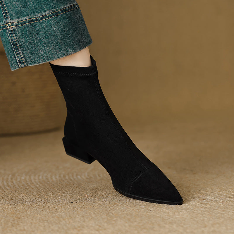 Black women's pointed-toe ankle boots with block heel, worn with cuffed denim
