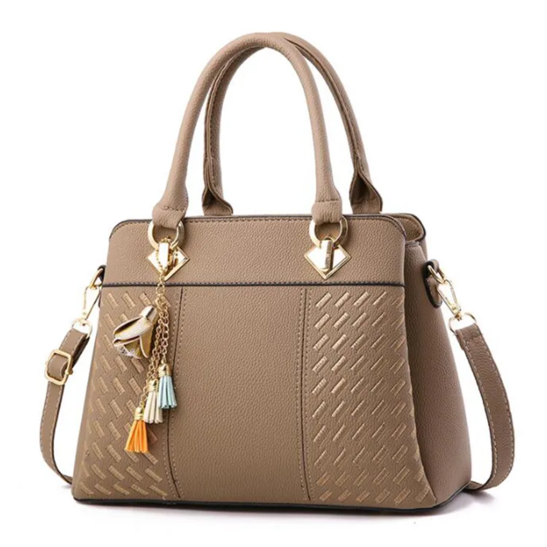 Taupe textured shoulder bag with top handles, tassel charms, gold-tone hardware, side strap