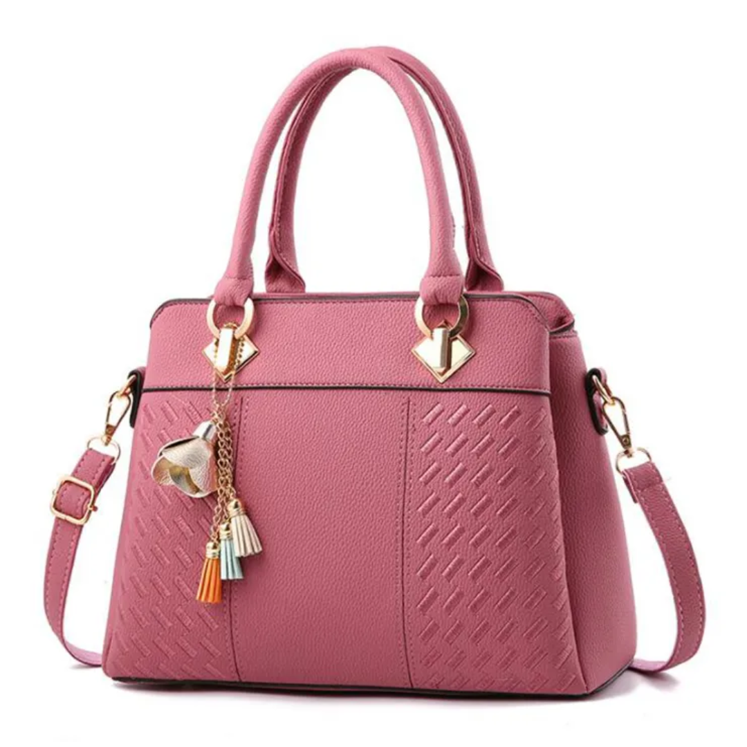 Pink women’s shoulder bag with textured front panel, tassel charm, and side straps