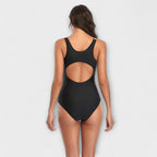 One-piece swimsuit back view with round cutout, black fabric with yellow strap detail.