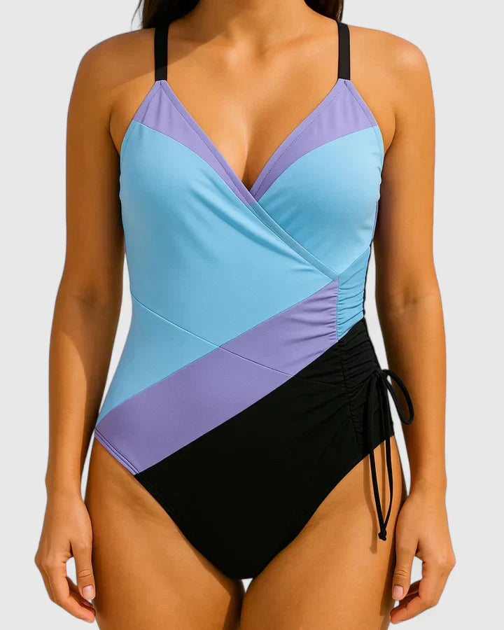 One-piece wrap swimsuit with blue and purple panels, ruched waist, side drawstring tie