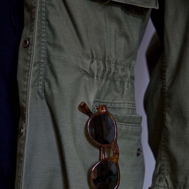 Close-up of green field jacket with brown button and stitching detail
