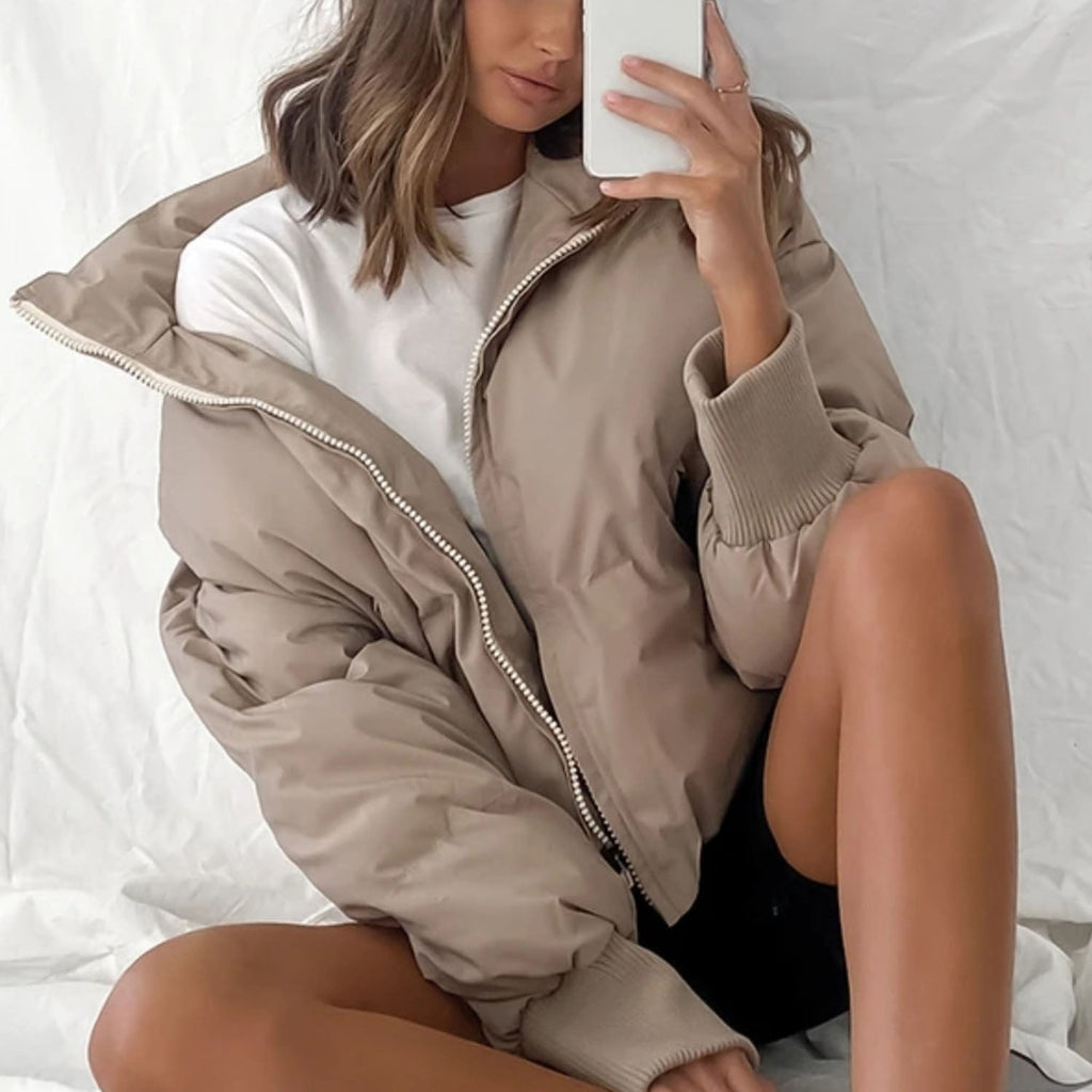 Beige short puffer jacket with hood and full zipper, paired with dark shorts