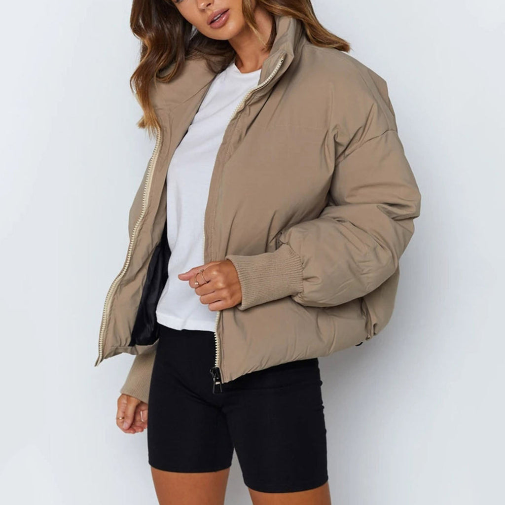 Beige cropped puffer jacket with stand collar, zip front, and ribbed cuffs