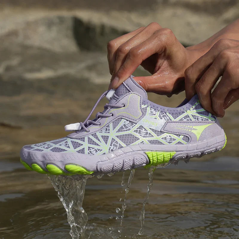 Light gray waterproof barefoot sneakers with lime green soles, worn in flowing water