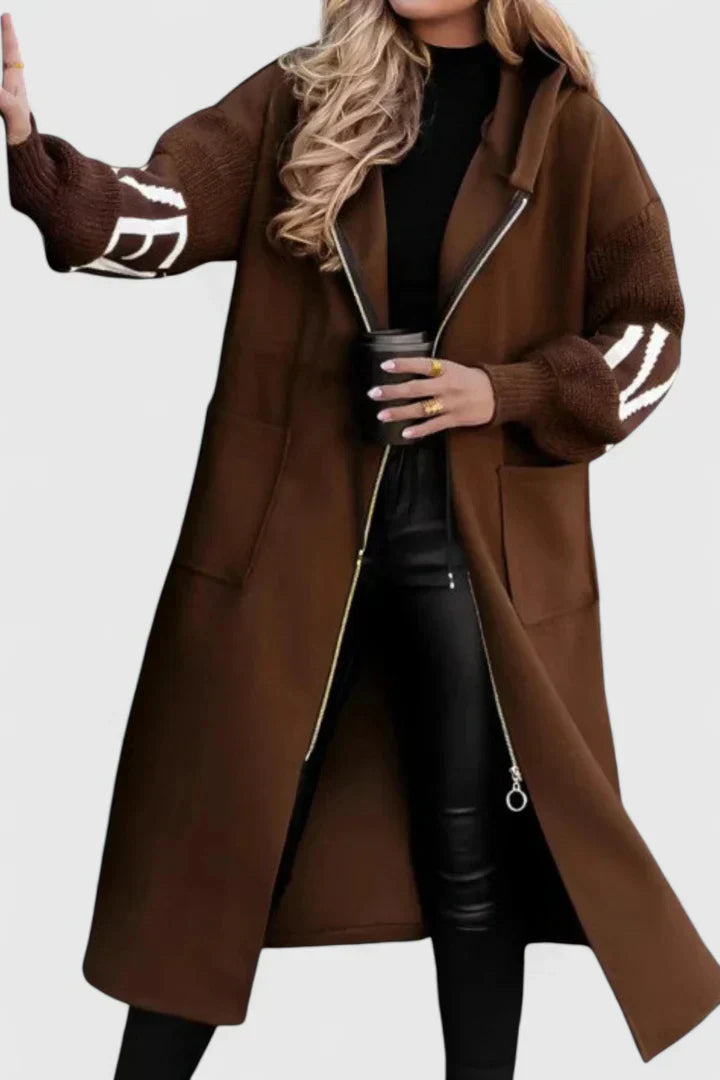 Brown hooded long coat with front zip, drawstring, patch pockets, and graphic sleeve details.